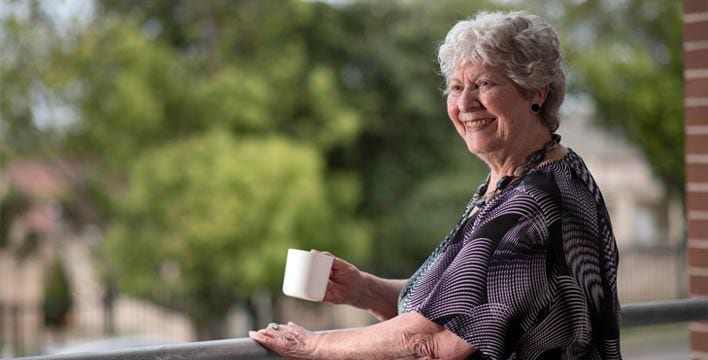 content-07 lady on balcony drinking a cup of tea - 'retirement villages near me' concept